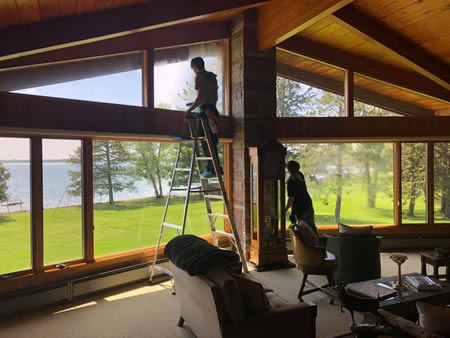 Technician cleaning interior windows near leech lake shoreline